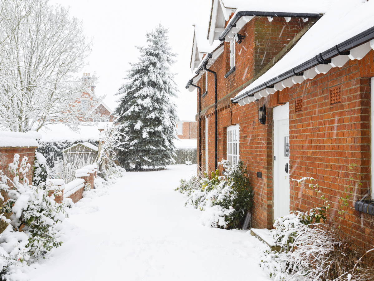 A cottage and garden covered in snow to represent the challenge of moving house in Winter.